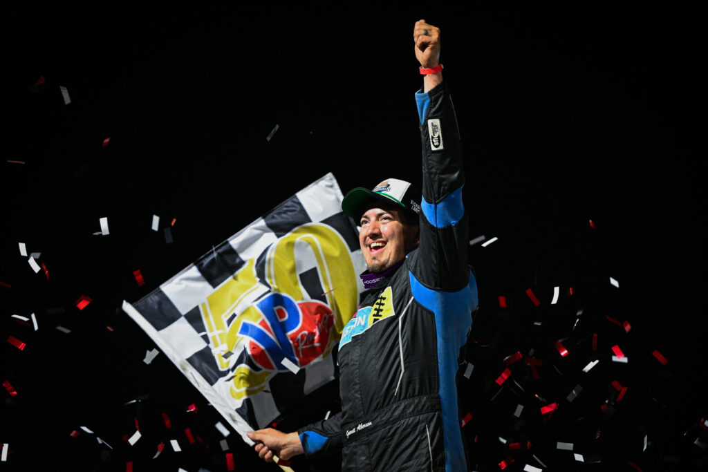 Garrett Alberson in victory lane with checkered flag at Volusia Speedway celebrating his World of Outlaws Late Models win.