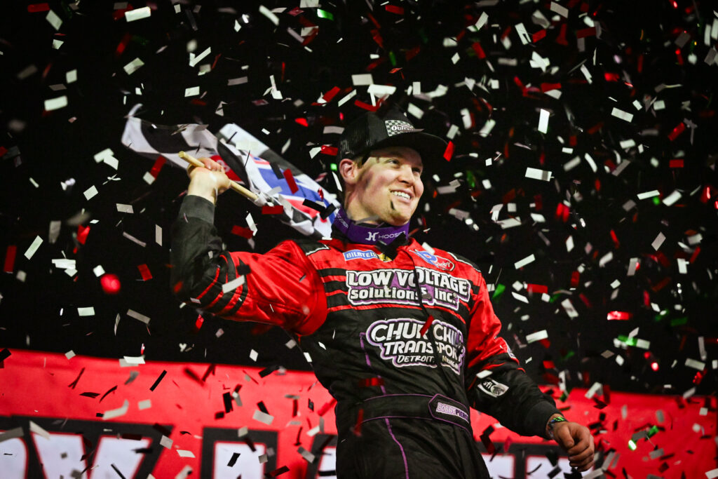 Bobby Pierce celebrates in victory lane at Swainsboro speedway, waving the checkered flag with confetti falling all around him