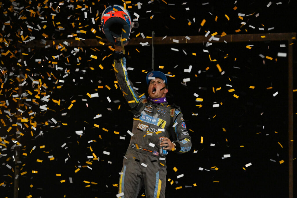 Nick Hoffman with his helmet raised and confetti flying in victory lane at the Swamp Cabbage 100 at Hendry County Speedway.